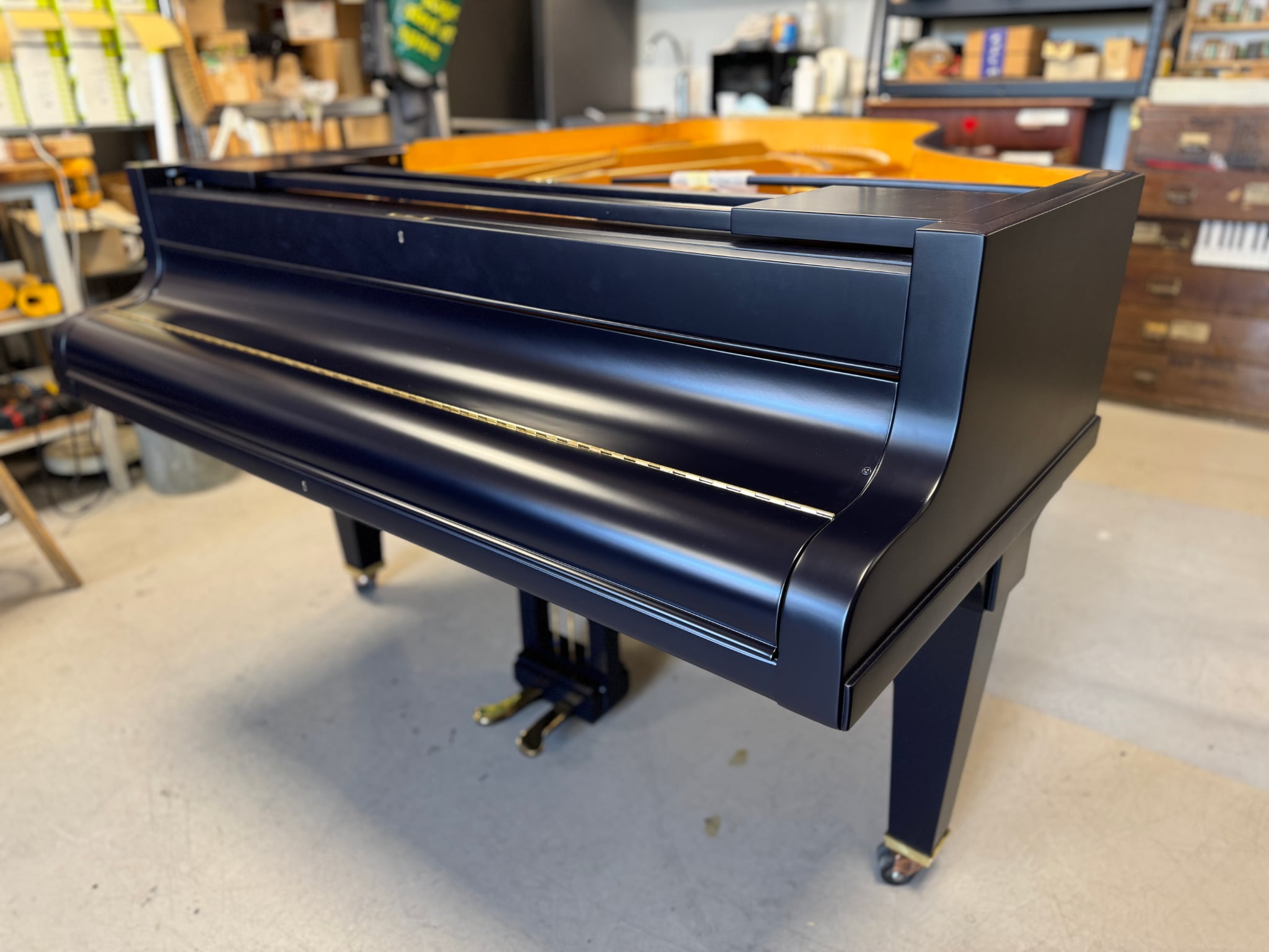 The same grand piano after restoration, refinished in matte dark blue