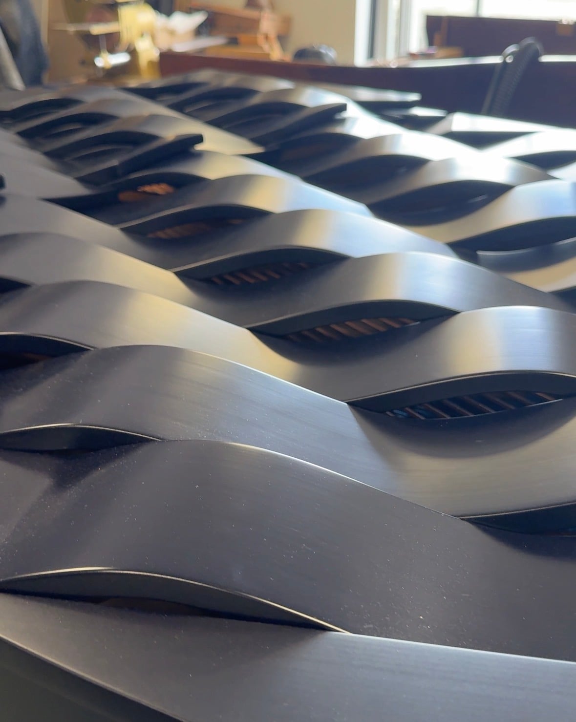Close-up of the Wave piano’s carved lid: rows of curved, dark blue ribs