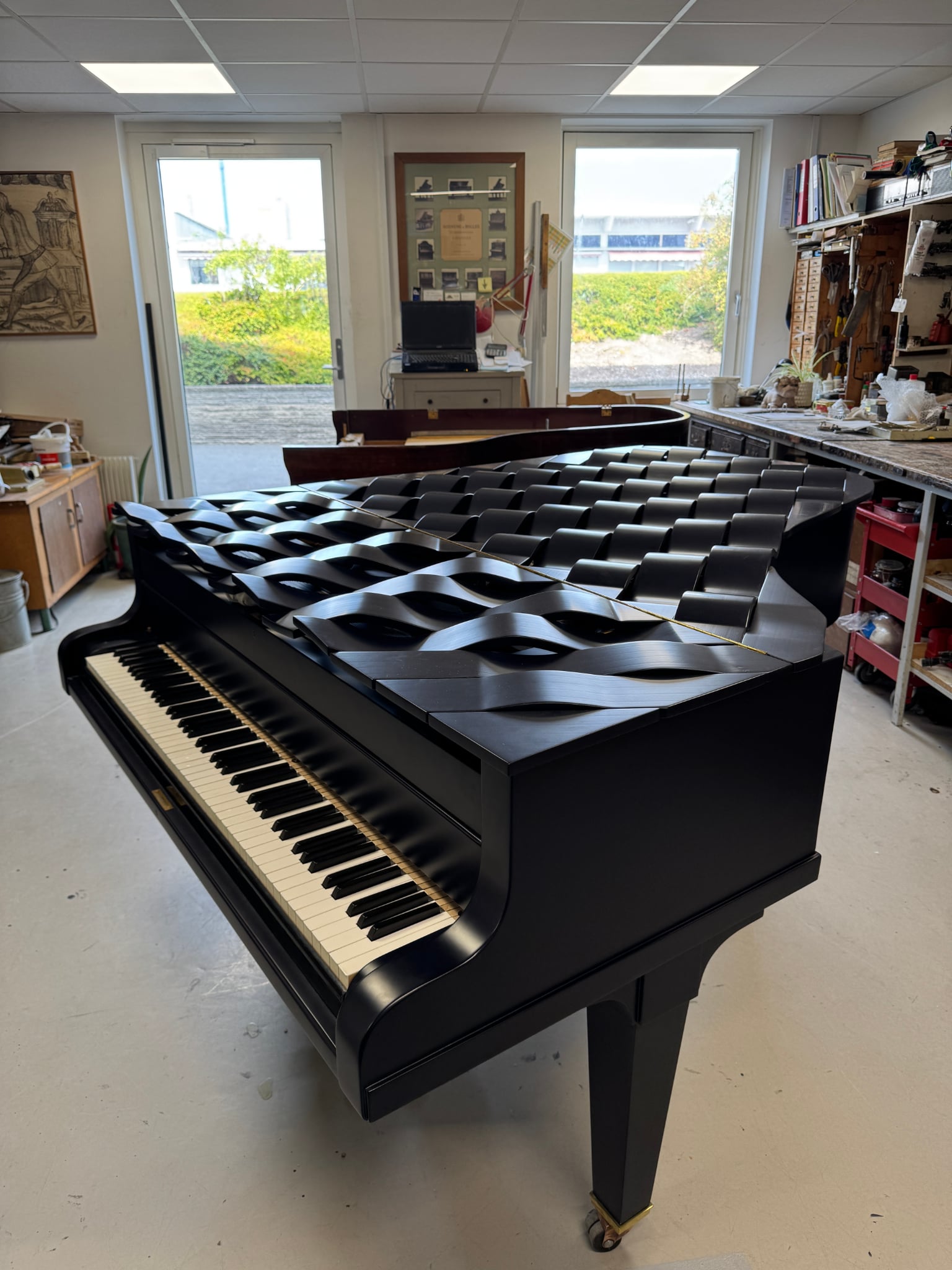 The Wave piano: a dark blue grand piano with a sculpted, wave-carved lid