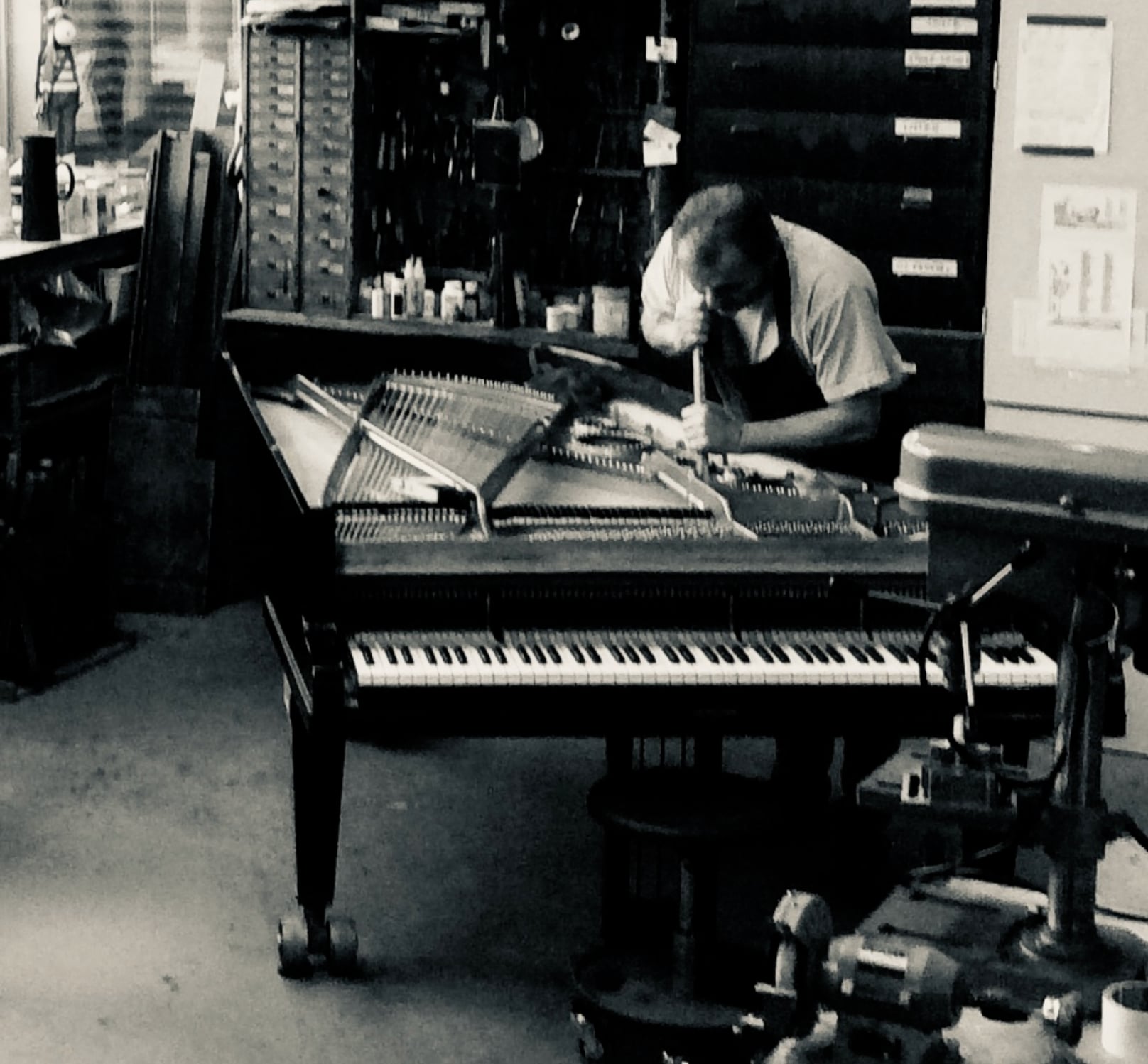 A piano maker restoring the strings of a grand piano at the Piano Sode workshop
